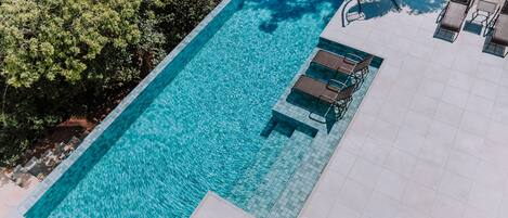 A rectangular swimming pool with clear blue water, surrounded by a tiled deck.