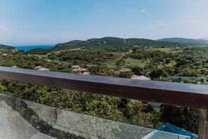 A balcony with a view of a lush green landscape, including hills and a distant body of water.