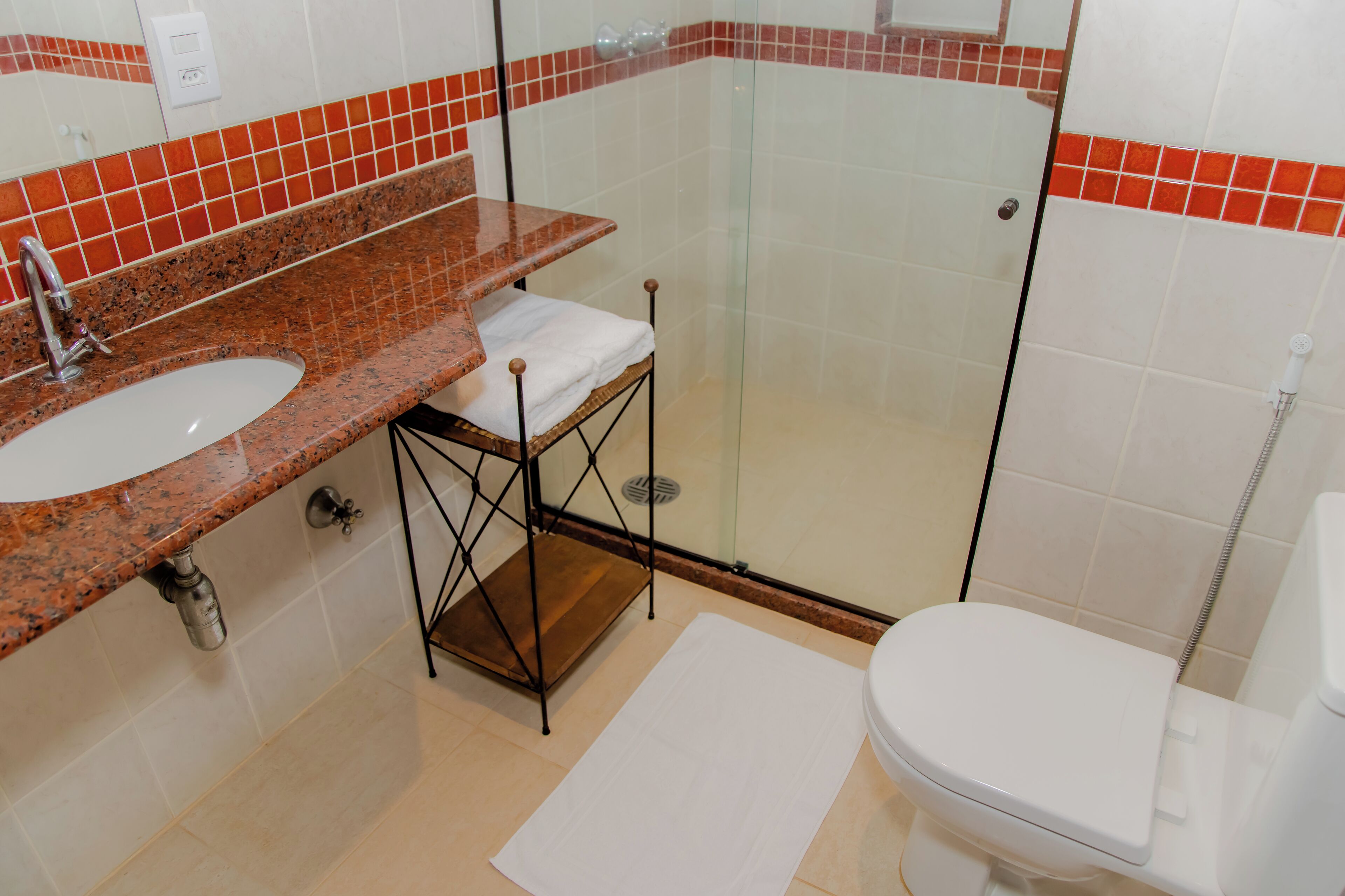 Baño con lavamanos de encimera de granito, cabina de ducha de vidrio y inodoro blanco.