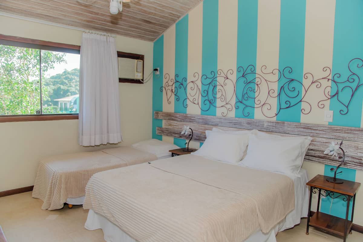 A hotel room with two beds, a window with a curtain, and a decorative wall with vertical stripes and a metal design.