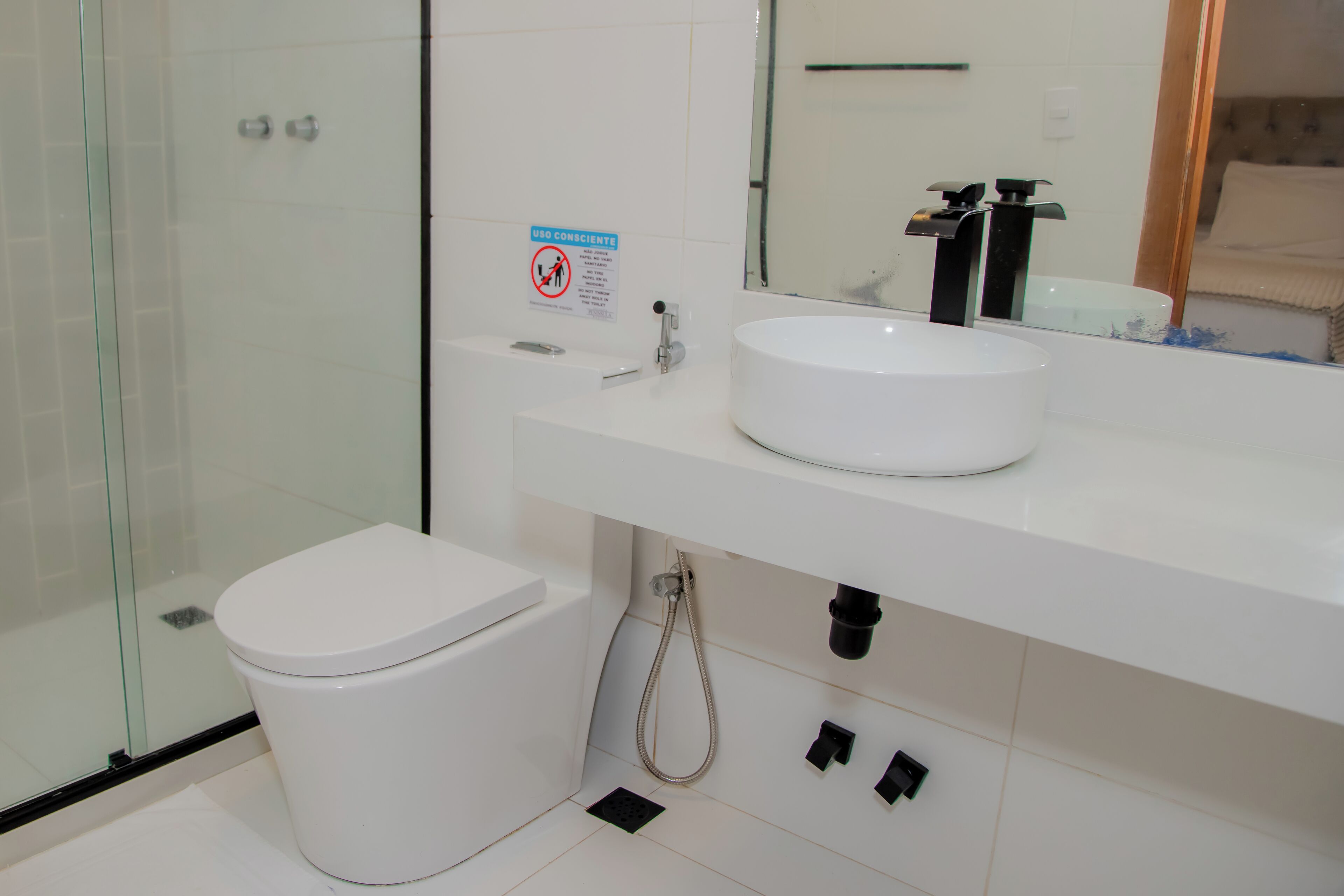 Een moderne badkamer met een douchecabine van glas, een wit toilet en een wit wastafelmeubel met spiegel.