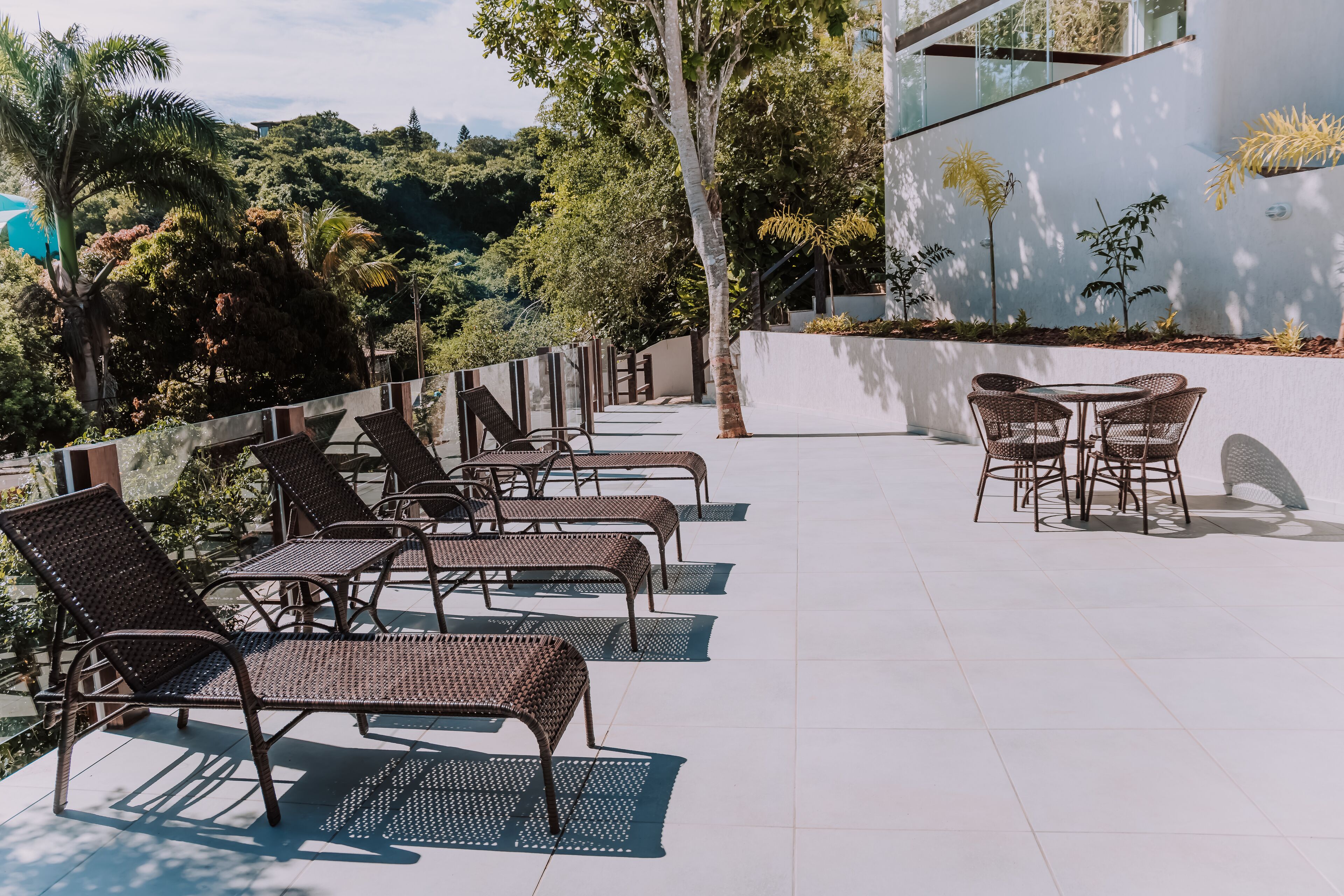 A terrace with wicker furniture and a view of a lush, green hillside.
