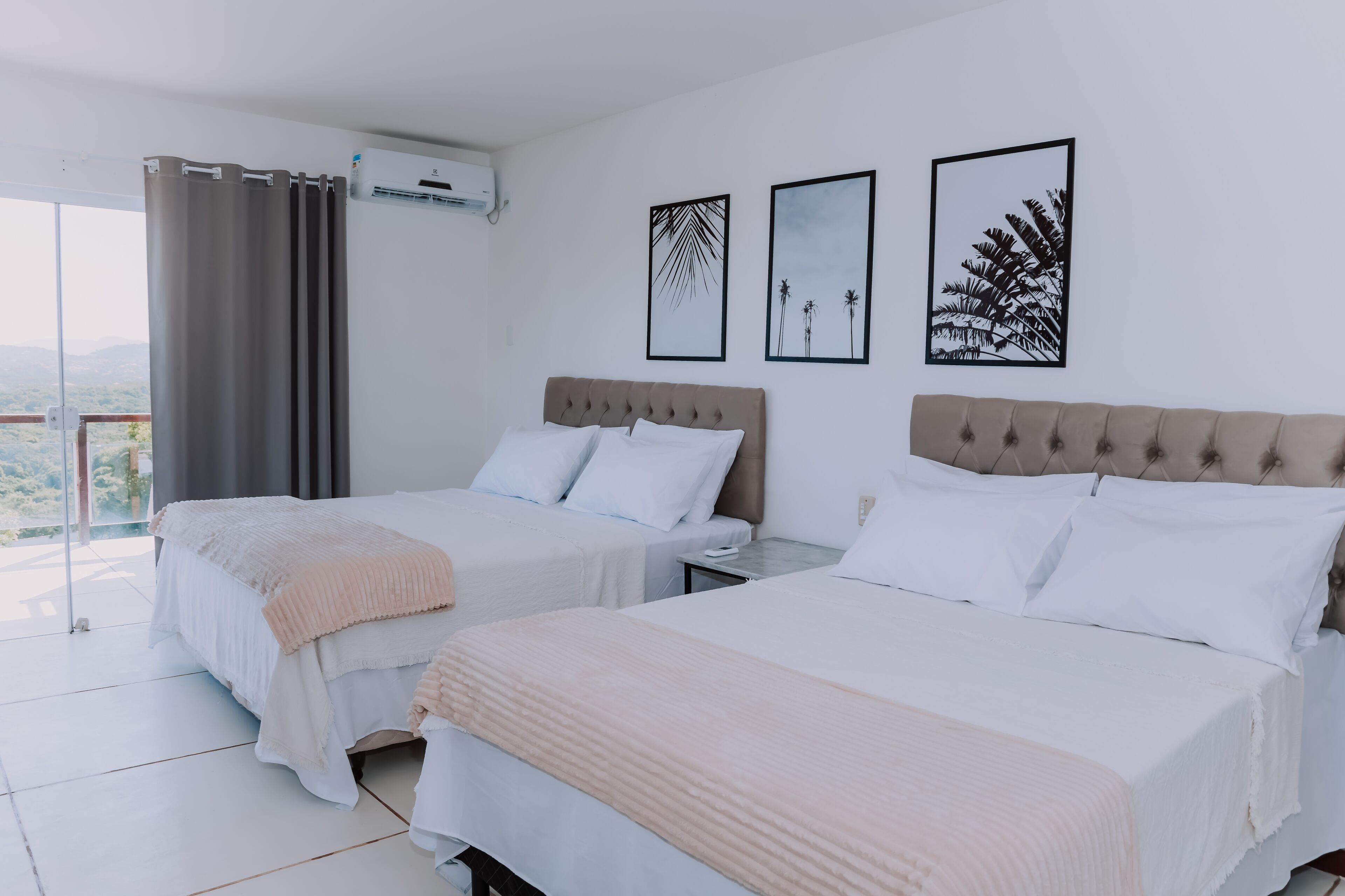 A hotel room with two beds, a balcony, and artwork on the walls.