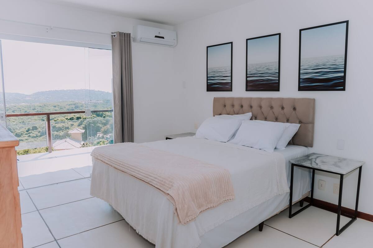 A bedroom with a large bed, a bedside table, and three framed pictures on the wall.