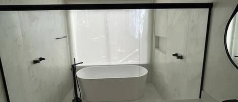 A modern bathroom with a freestanding bathtub, a glass-enclosed shower, and a white sink.