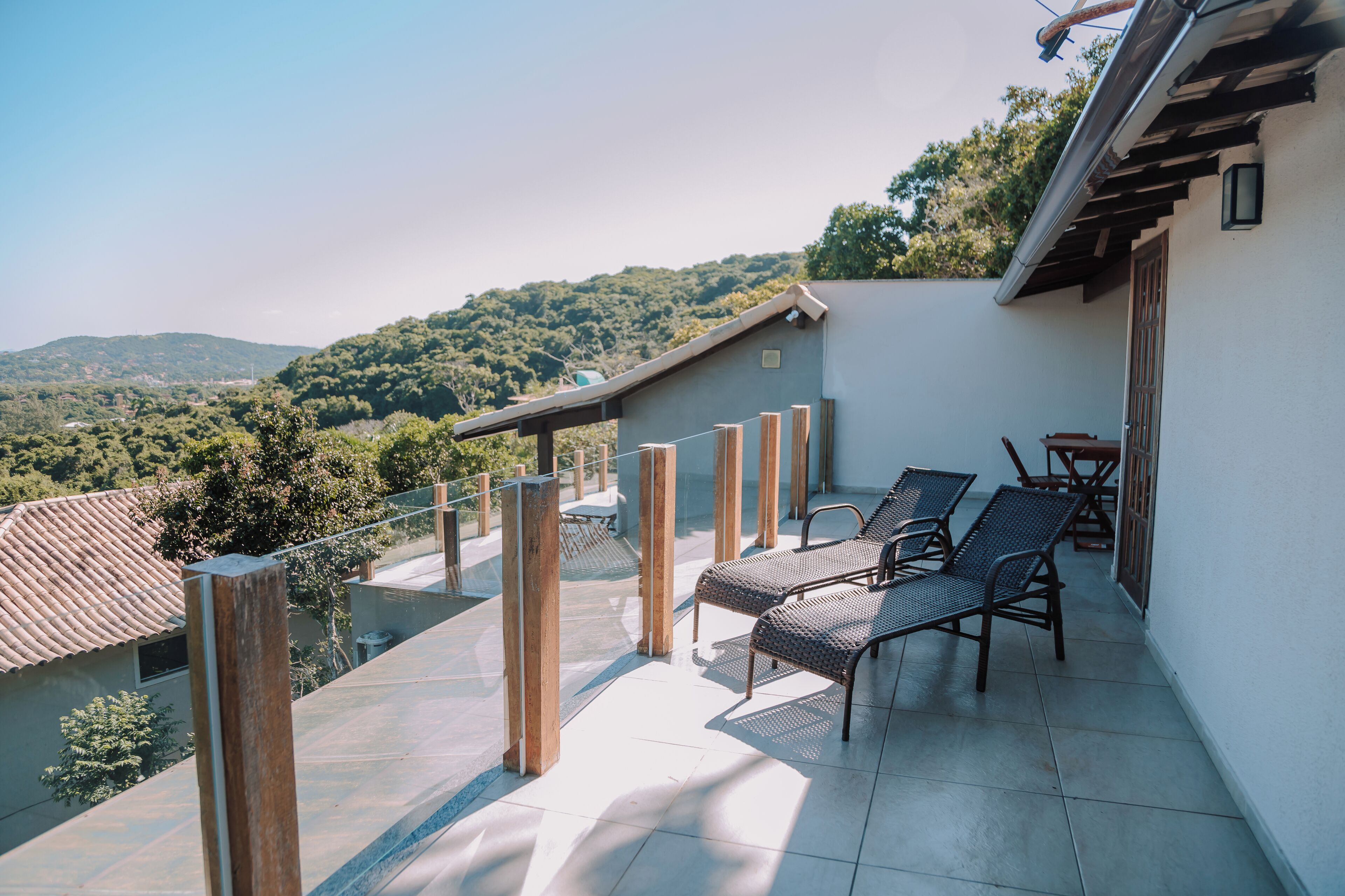Un balcon donnant sur un paysage montagneux, avec des piliers en bois et une table entourée de chaises.