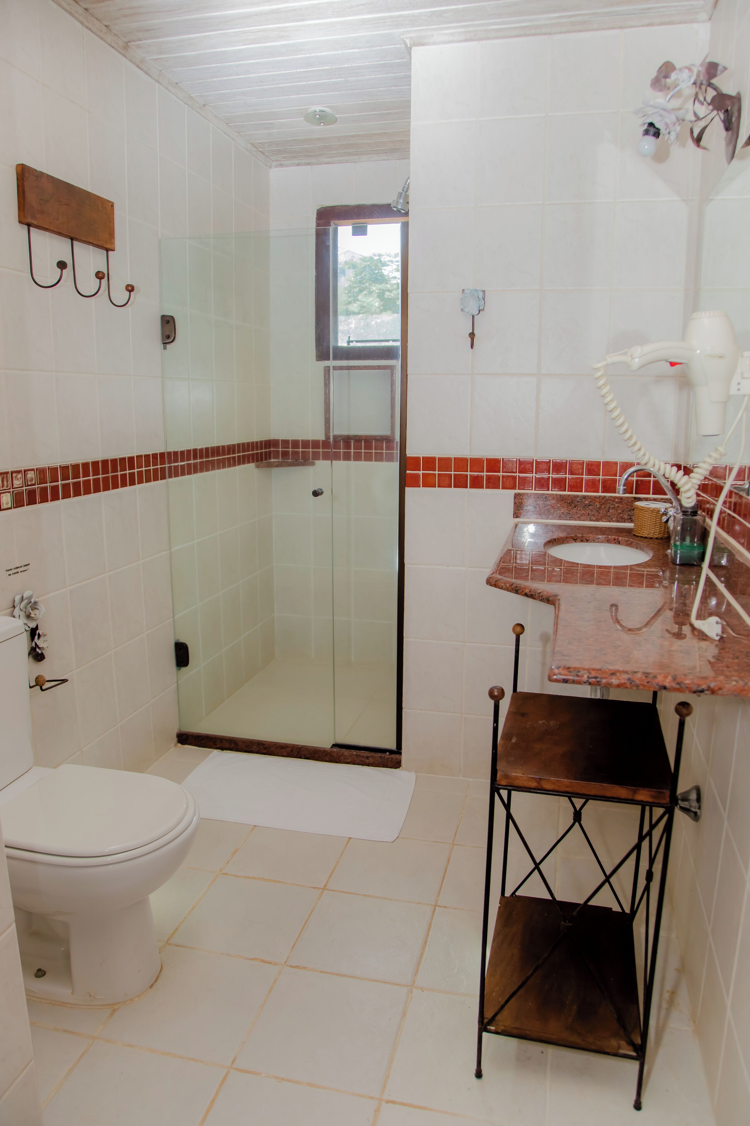 Et badeværelse med toilet, bruseniche, vask med håndklæder og et lille bord.