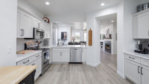 A modern kitchen with white cabinetry, stainless steel appliances, and a central island.