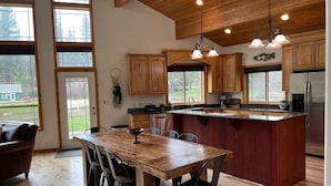 Una cocina moderna con armarios de madera, una isla grande y una zona de comedor con mesa y sillas de madera.