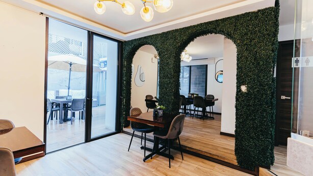 Een modern interieur met een eethoek, een grote spiegel en een groene wand met een trellispuntpatroon.