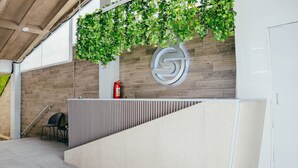 Een receptie met een houten wand, een groot logo, een brandblusser en een stoel.