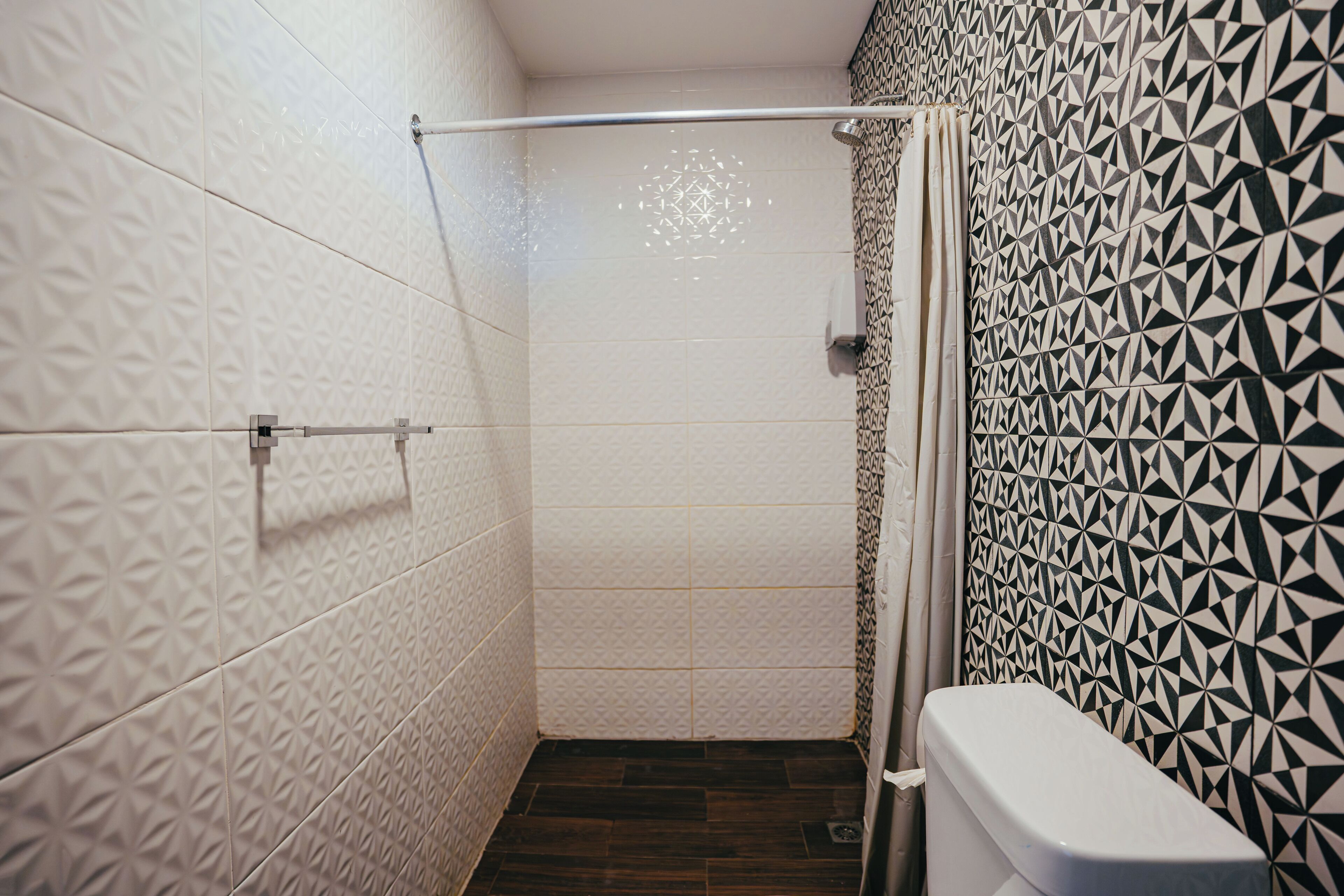 Un baño con baldosas estampadas, zona de ducha y un inodoro.