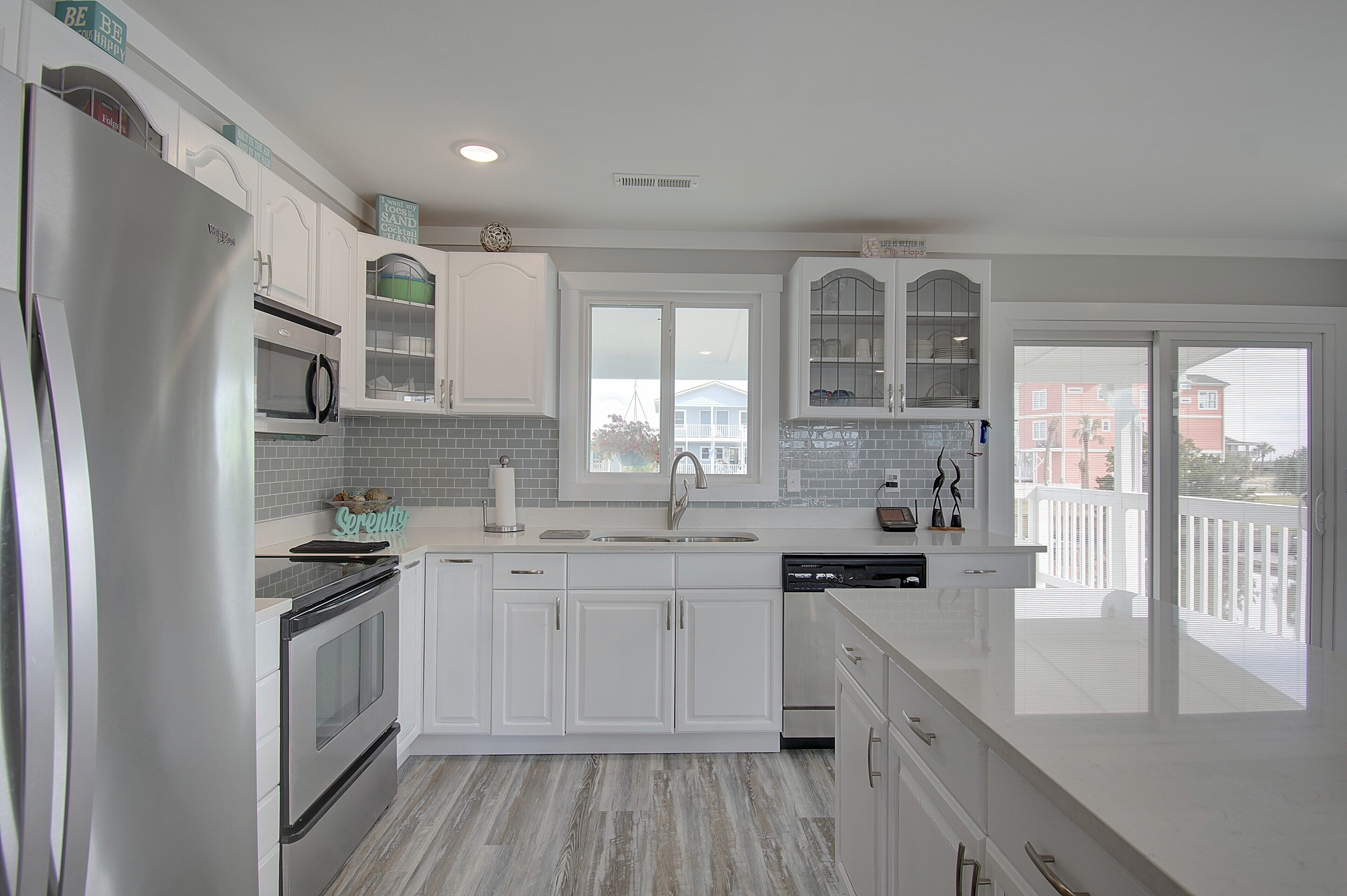 A modern kitchen with white cabinetry, a stainless steel refrigerator, a built-in oven, and a dishwasher.