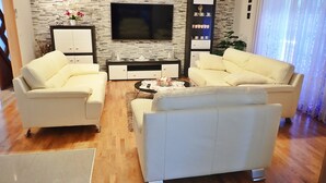 Ein modernes Wohnzimmer mit zwei weißen Sofas, einem Couchtisch, einem Fernseher und einem dekorativen Regal.