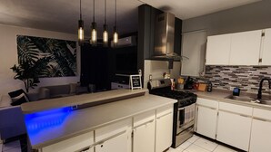 Une cuisine moderne dotée d’un îlot central, d’appareils électroménagers en acier inoxydable et d’un pare-feu.