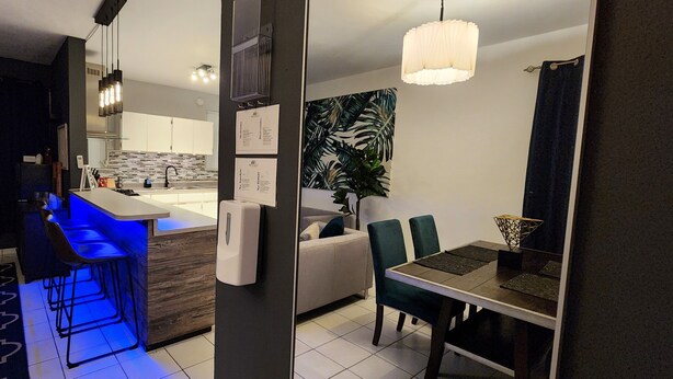 Une cuisine moderne avec un coin bar, une table à manger avec des chaises et un espace salon avec un canapé.