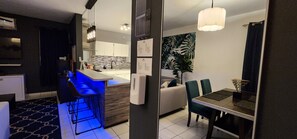 Una cocina moderna con barra, una mesa de comedor con sillas y una sala de estar con sofá.