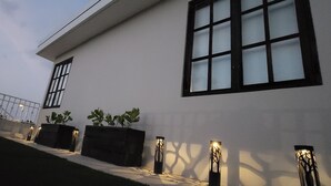 Un bâtiment moderne doté de grandes fenêtres, d’une façade blanche et d’un éclairage extérieur.