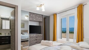 A modern bedroom with a large bed, a TV, and a view of the outdoors. - Vacation home Matea by Interhome (Krk/Dobrinj)
