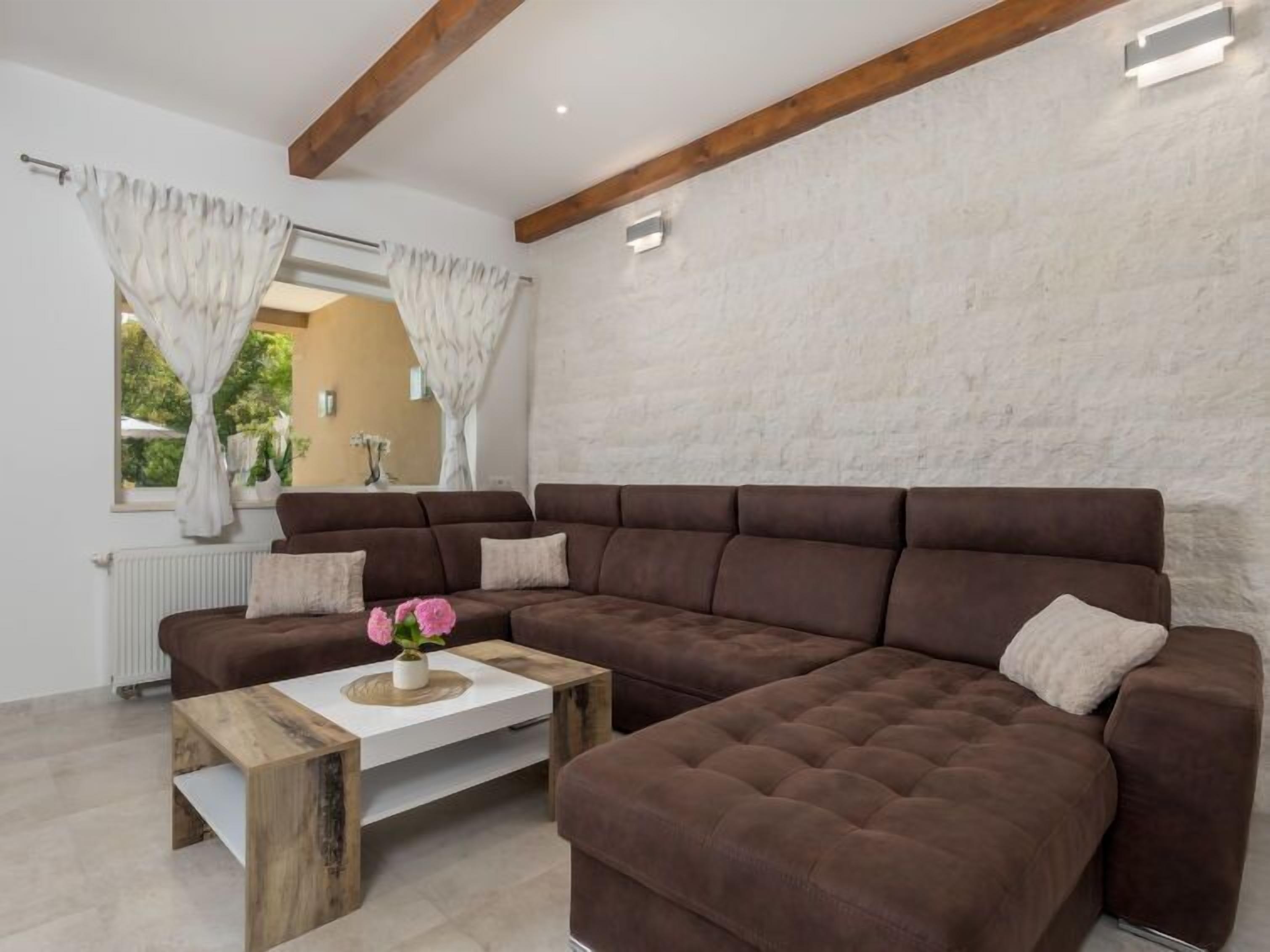 A modern living room with a brown sectional sofa, a wooden coffee table, and a white wall.