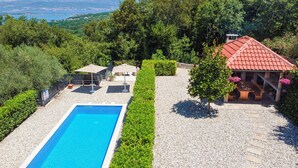 A rectangular swimming pool with a clear blue water, surrounded by a gravel area and bordered by neatly trimmed hedges. - Vacation home Matea by Interhome (Krk/Dobrinj)