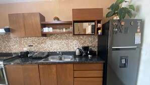 A kitchen with wooden cabinets, a black refrigerator, a coffee maker, and a plant. - 300MB/S Wifi with an amazing pool 3 Bed 2.5bath house (Mérida)