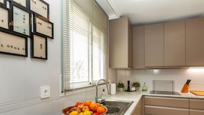 Een keuken met een marmeren aanrechtblad, een spoelbak en houten kastjes.