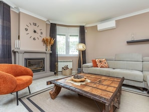 Un salon avec une cheminée, un canapé, une table basse et une horloge au mur.