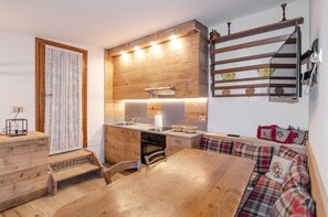 Une cuisine compacte dotée de meubles en bois, d’un four encastré et d’un coin repas avec une table et des chaises en bois.