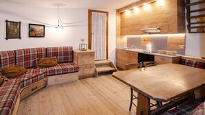 A cozy living area with a sofa, a dining table, and a kitchen area. - Tofana Cosy Studio - 2 persons (Cortina d´Ampezzo)
