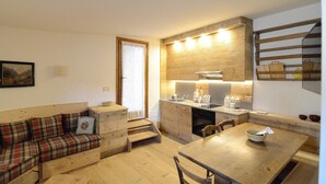 A compact living space with a sofa, dining table, kitchen area, and a staircase. - Tofana Cosy Studio - 2 persons (Cortina d´Ampezzo)