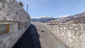 A stone wall with a narrow road, a lamp post, and a mountain view. - Tofana Cosy Studio - 2 persons (Cortina d´Ampezzo)