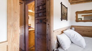A wooden interior with a bed, a mirror, and a door leading to a bathroom. - Tofana Cosy Studio - 2 persons (Cortina d´Ampezzo)
