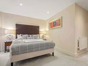 A bedroom with a bed, bedside lamps, a nightstand, a radiator, and a framed picture on the wall. - Lovely apartment for 2 people with WIFI, TV and balcony (London)