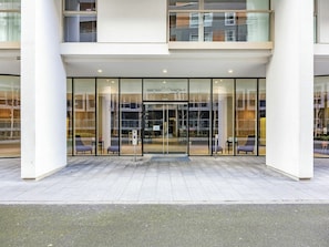 A modern hotel entrance with glass doors, a covered outdoor seating area, and a visible sign for 'Denison Hotel'.
