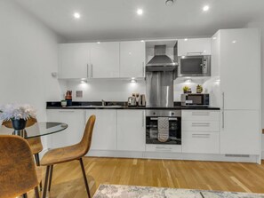A modern kitchen with white cabinets, stainless steel appliances, and a wooden dining table with chairs.