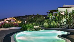 Une piscine à la forme originale, avec des bords ondulés, entourée d’une végétation luxuriante et de plantes tropicales.
