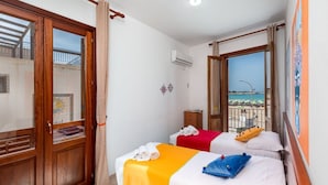 Une chambre d’hôtel avec deux lits, un balcon donnant sur la plage et un climatiseur fixé au mur.