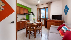 A compact living space with a dining area, kitchenette, and a seating area with a TV. - Beach Apartments - Two-Room (San Vito Lo Capo)