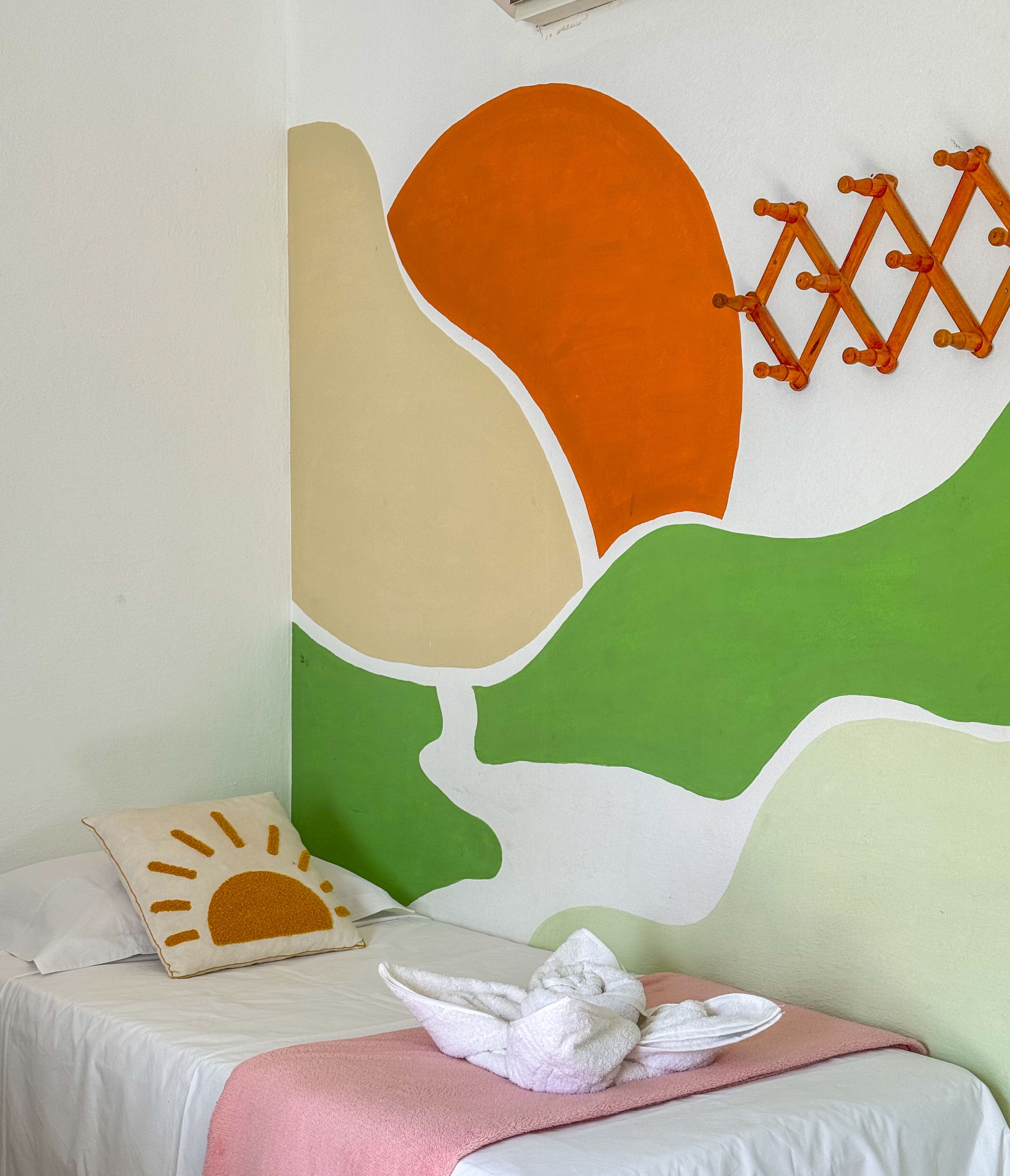 Un dormitorio con cama, almohadas y una decoración en la pared.