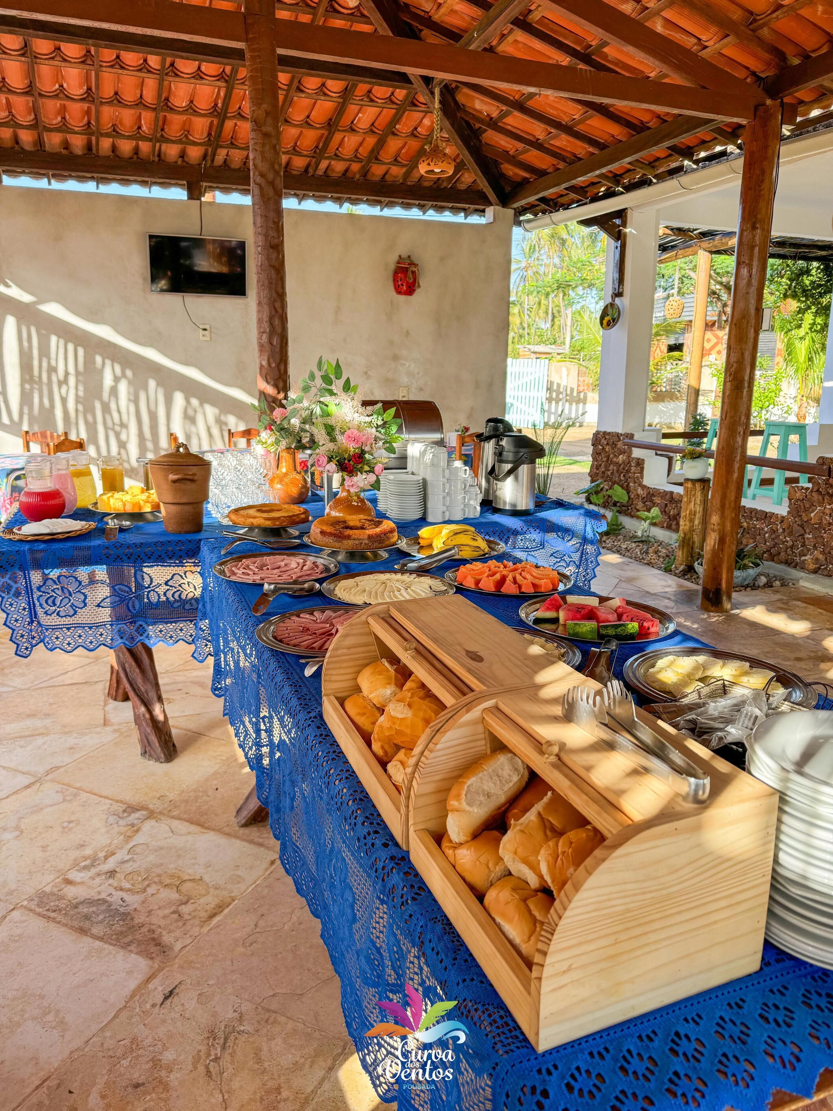 Disposición de buffet con diversos alimentos y un mantel de encaje azul.