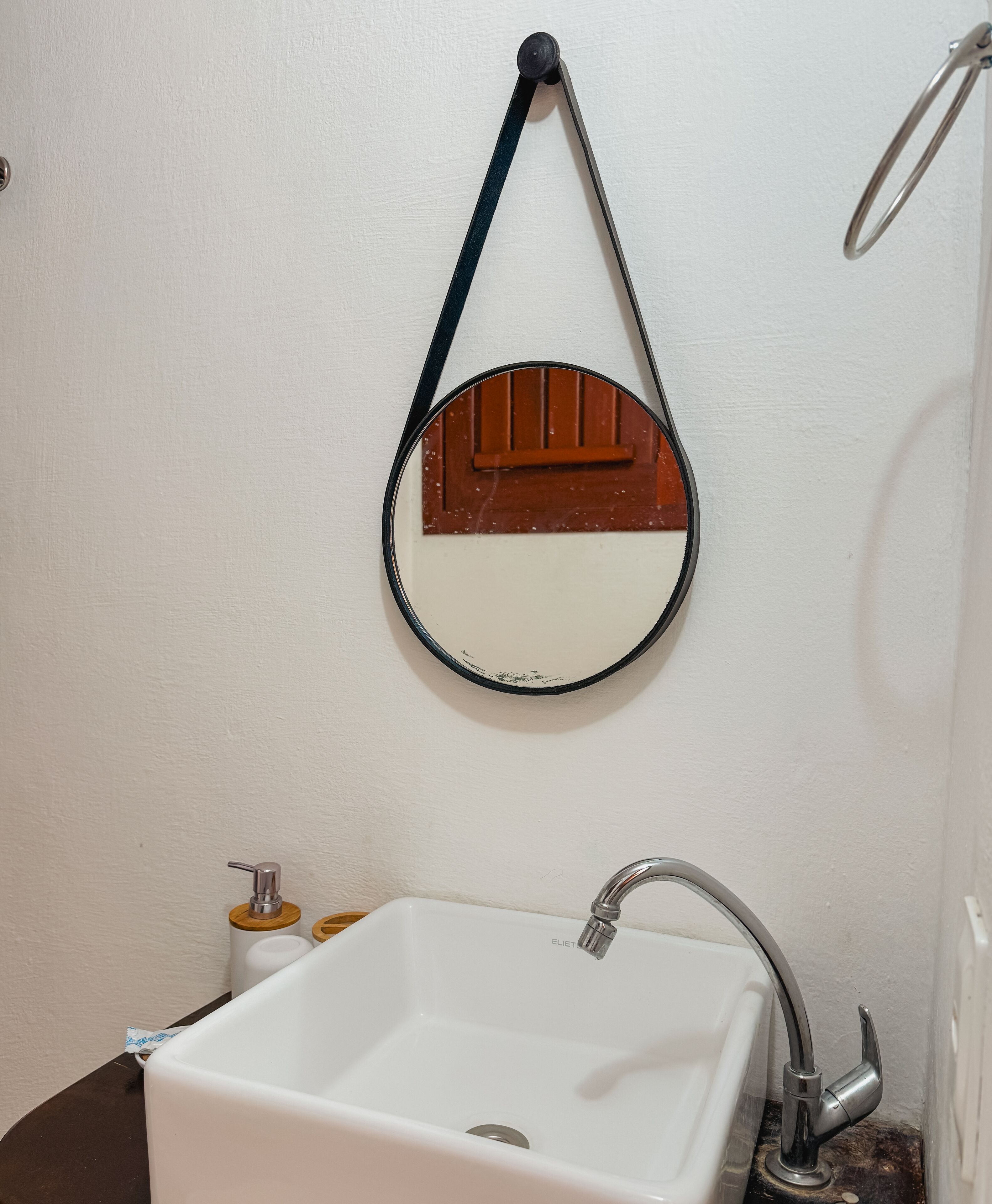 A bathroom with a white sink, a mirror with a wooden frame, and a towel hanging on a hook.