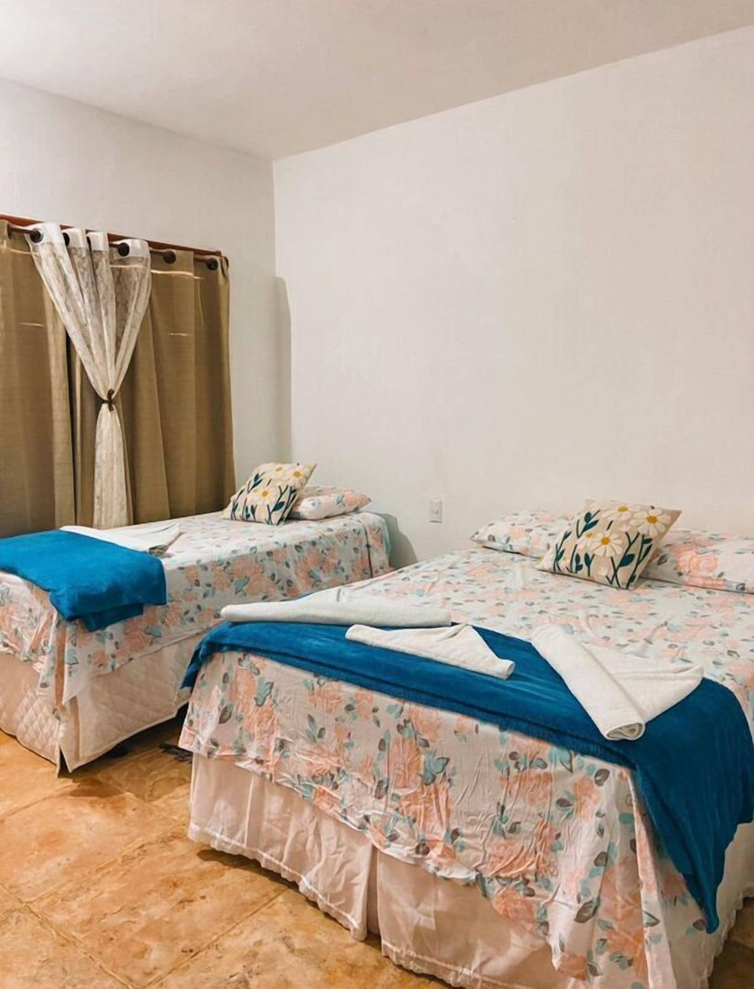 A hotel room with two single beds, each with floral bedding and blue headboards.