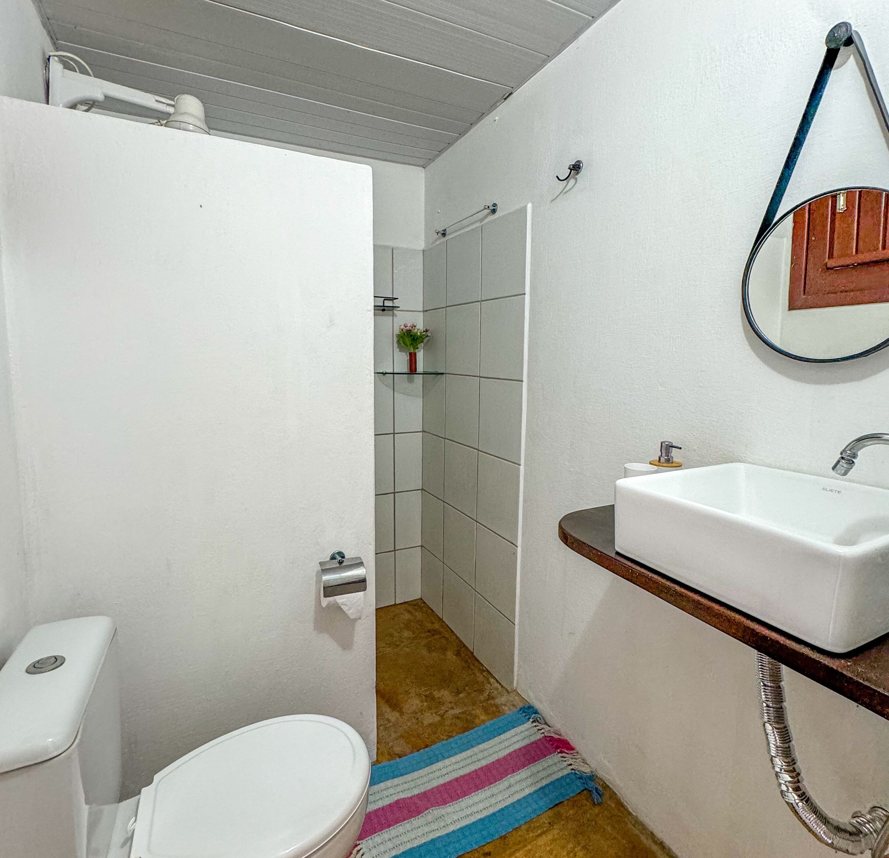 A bathroom with a white toilet, a sink, and a shower area.