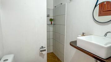 Un baño con inodoro blanco, lavamanos y zona de ducha.