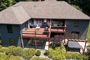 Una casa de dos pisos con terraza, mobiliario exterior y un pequeño jardín.