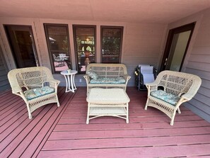 A covered porch with wicker furniture, including two chairs and a small table.
