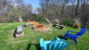 Un espacio al aire libre con una chimenea, bancos y sillas.