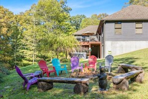 A backyard with a fire pit, colorful Adirondack chairs, and a bear statue.
