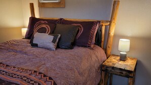 A bed with a patterned blanket, multiple pillows, and two bedside lamps on wooden nightstands.